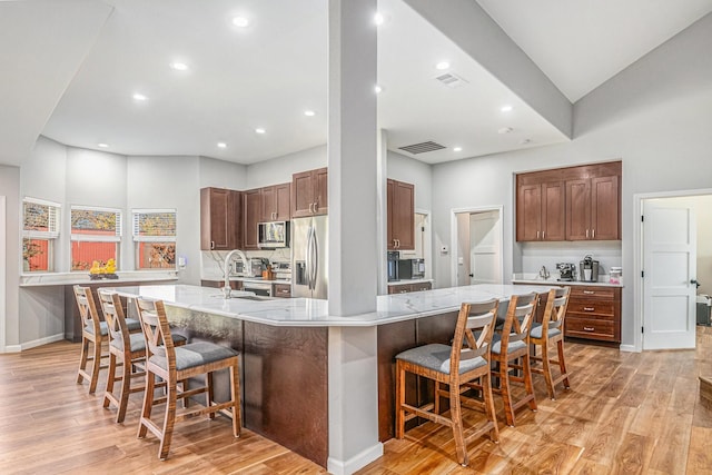 kitchen featuring stainless steel appliances, a large island, a breakfast bar, and light hardwood / wood-style flooring