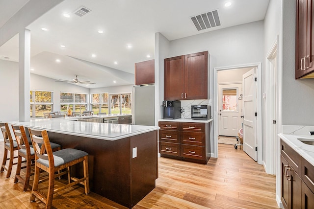 kitchen featuring stainless steel appliances, light wood-type flooring, ceiling fan, a breakfast bar, and lofted ceiling