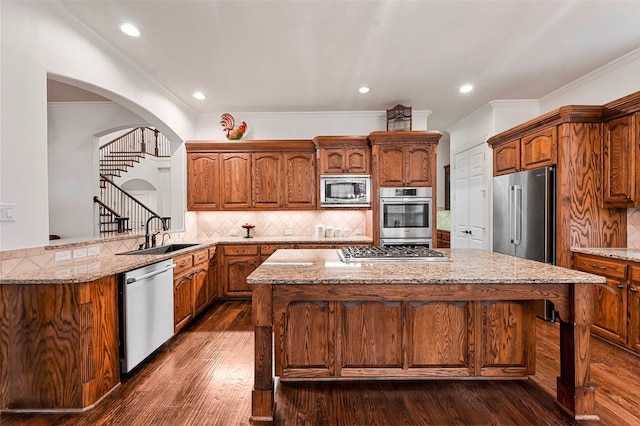 kitchen featuring sink, crown molding, dark wood-type flooring, stainless steel appliances, and tasteful backsplash