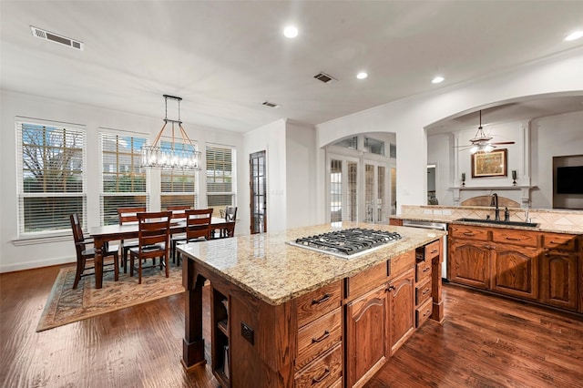 kitchen with dark wood-type flooring, sink, decorative light fixtures, a center island, and stainless steel gas stovetop