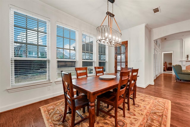 dining area featuring ornamental molding, hardwood / wood-style floors, and an inviting chandelier