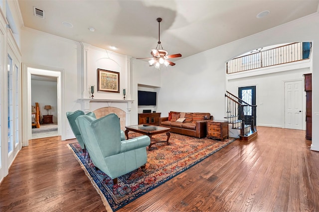 living room with hardwood / wood-style flooring, ornamental molding, a tile fireplace, and ceiling fan