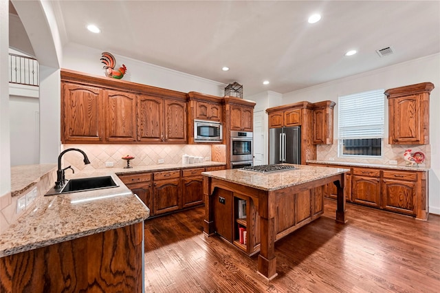 kitchen with sink, light stone counters, dark hardwood / wood-style floors, a kitchen island, and stainless steel appliances