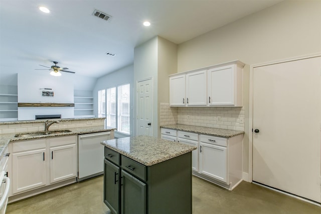 kitchen featuring light stone counters, sink, dishwasher, a center island, and white cabinetry