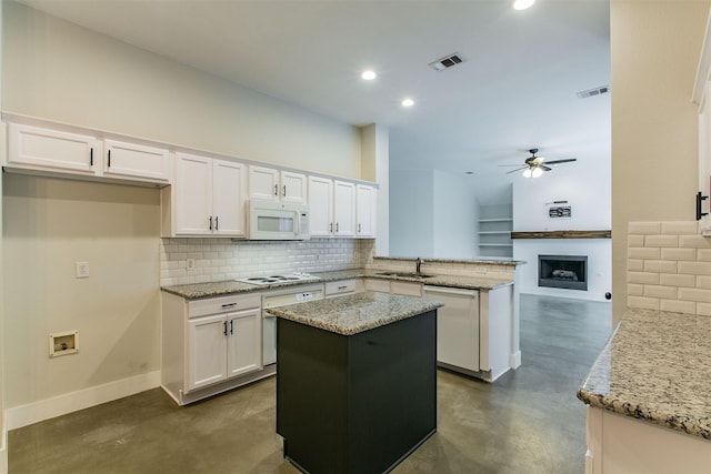 kitchen featuring kitchen peninsula, light stone countertops, white cabinets, and white appliances