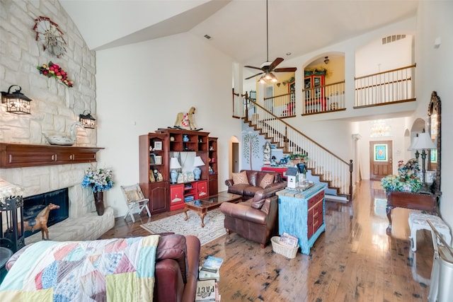 living room featuring a fireplace, hardwood / wood-style flooring, high vaulted ceiling, and ceiling fan