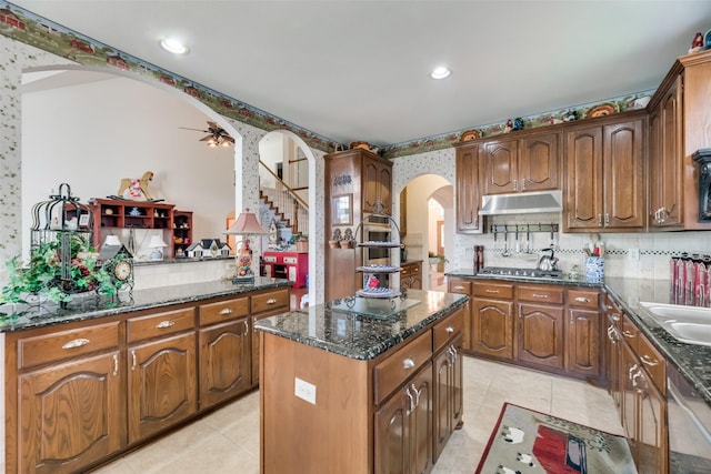 kitchen featuring ceiling fan, a center island, stainless steel appliances, and tasteful backsplash