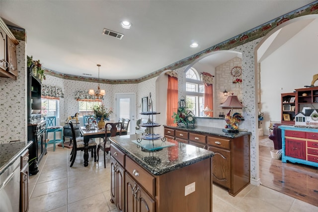 kitchen with a center island, a notable chandelier, dark stone countertops, pendant lighting, and light tile patterned flooring