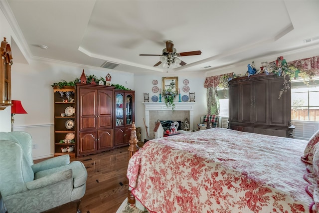 bedroom featuring a tray ceiling, ceiling fan, dark hardwood / wood-style flooring, and ornamental molding