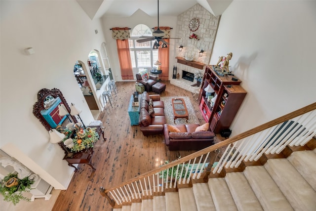 living room with hardwood / wood-style floors, ceiling fan, a fireplace, and high vaulted ceiling