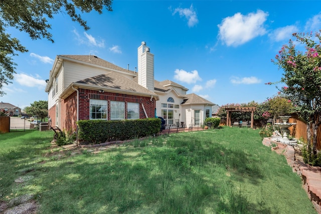 rear view of property featuring a pergola and a yard