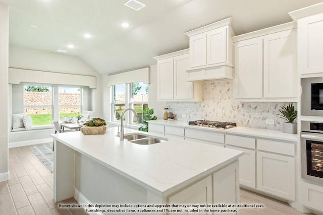 kitchen featuring white cabinets, appliances with stainless steel finishes, an island with sink, and sink