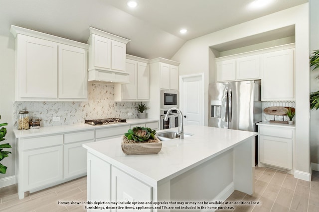 kitchen with white cabinetry, sink, stainless steel appliances, lofted ceiling, and a center island with sink