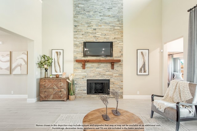 living room featuring a stone fireplace and a high ceiling