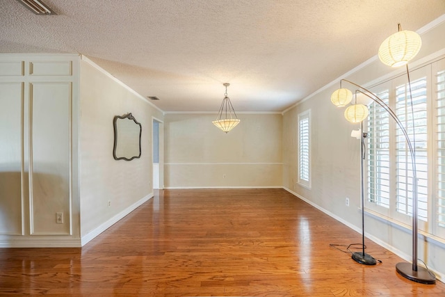 unfurnished dining area featuring hardwood / wood-style floors, a textured ceiling, and ornamental molding