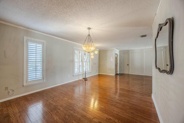 empty room featuring hardwood / wood-style floors, plenty of natural light, ornamental molding, and a textured ceiling