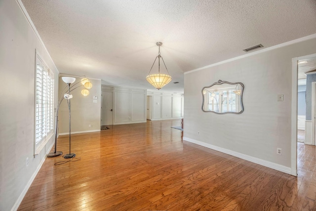 spare room featuring wood-type flooring, crown molding, and a healthy amount of sunlight