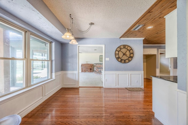 unfurnished dining area with wooden ceiling, a textured ceiling, and light hardwood / wood-style flooring