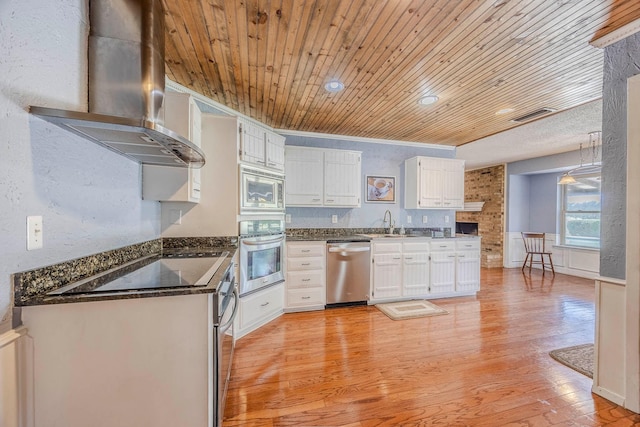 kitchen with white cabinetry, stainless steel appliances, wall chimney range hood, wood ceiling, and ornamental molding