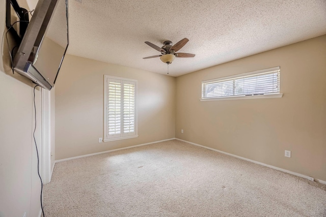 carpeted spare room featuring a textured ceiling and ceiling fan