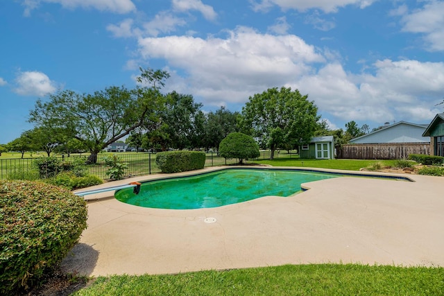 view of pool with a yard, a patio area, a diving board, and a storage shed