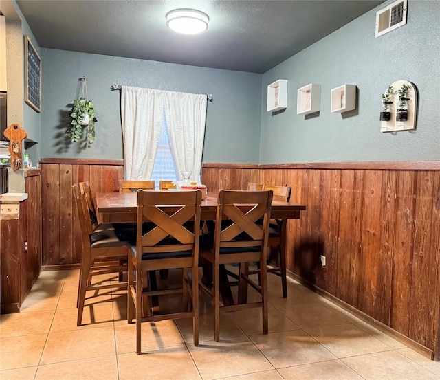 tiled dining space featuring wooden walls