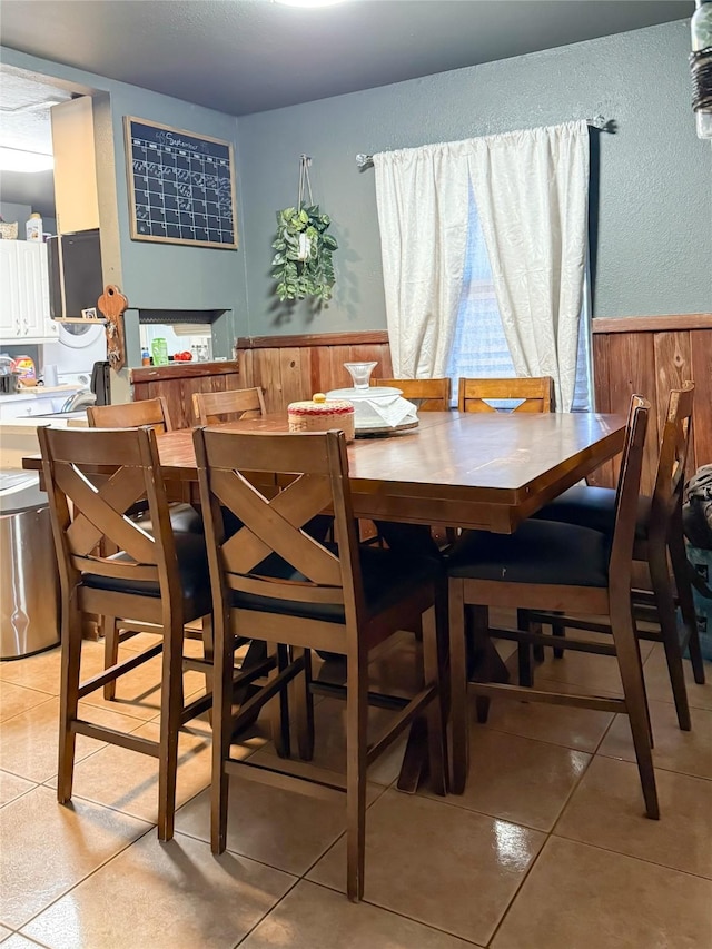 tiled dining room featuring wood walls