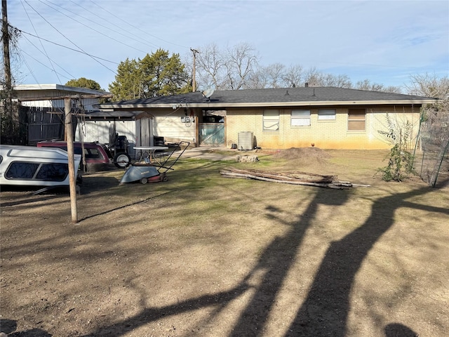 rear view of property with central AC unit and a lawn