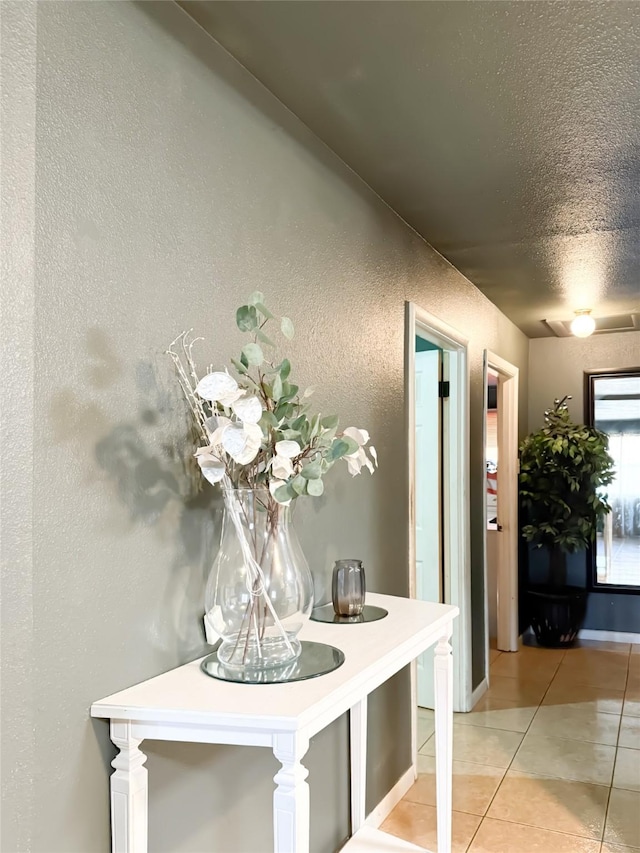 hall featuring light tile patterned flooring and a textured ceiling