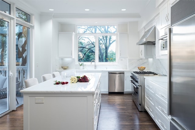 kitchen featuring a center island, wall chimney exhaust hood, tasteful backsplash, white cabinets, and high end appliances