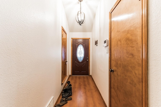 doorway to outside featuring wood-type flooring and a notable chandelier