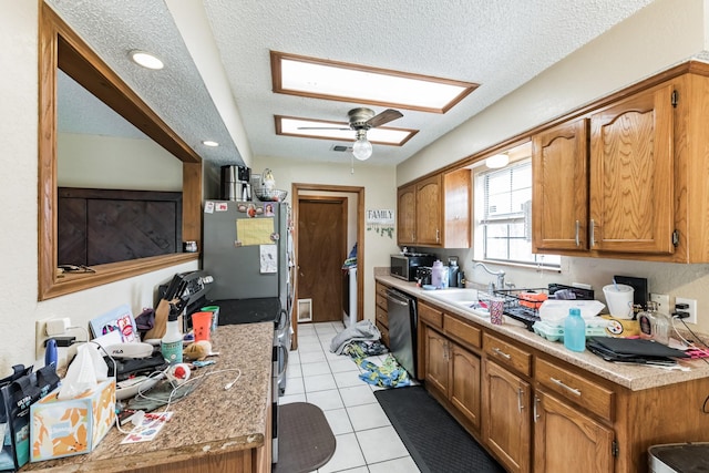 kitchen with sink, ceiling fan, a textured ceiling, light tile patterned flooring, and stainless steel appliances