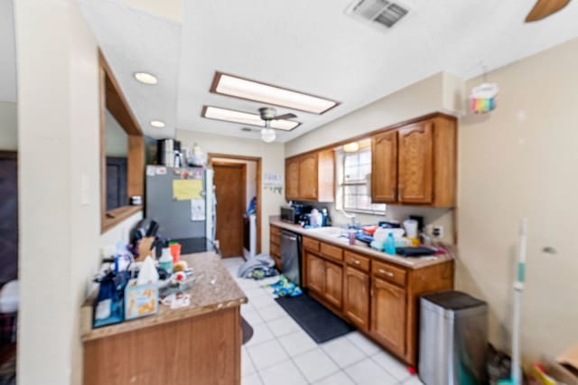 kitchen featuring refrigerator, a skylight, ceiling fan, light tile patterned floors, and dishwasher