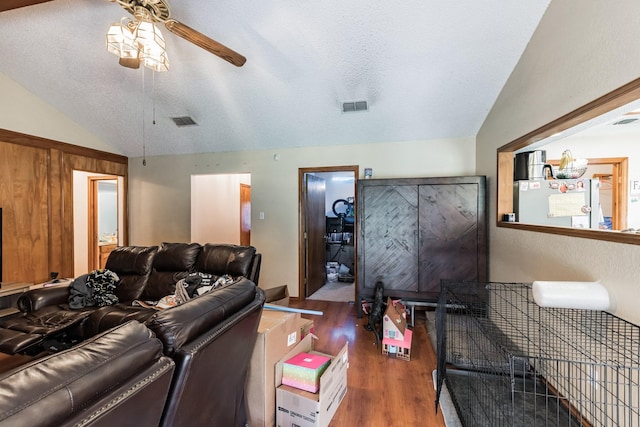 living room featuring dark hardwood / wood-style floors, ceiling fan, lofted ceiling, and a textured ceiling