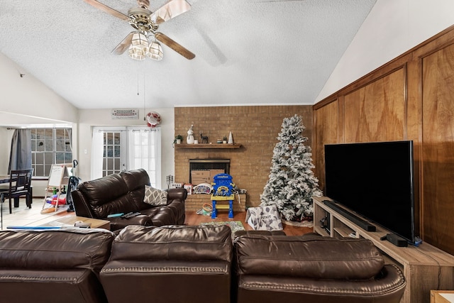 living room with a textured ceiling, ceiling fan, french doors, and vaulted ceiling