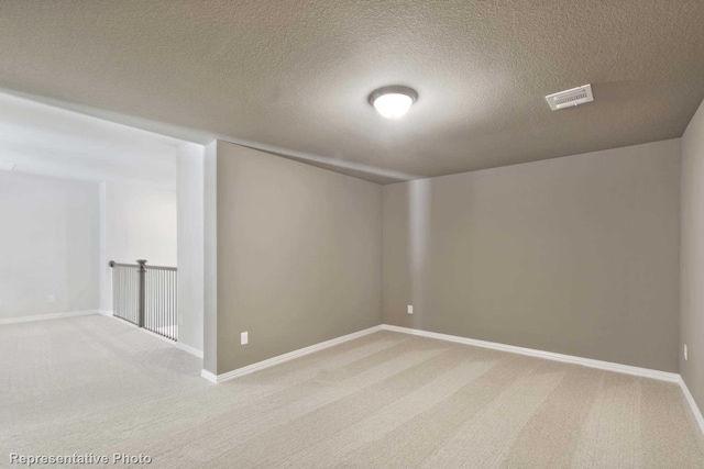 carpeted empty room featuring a textured ceiling