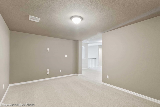 carpeted empty room featuring a textured ceiling