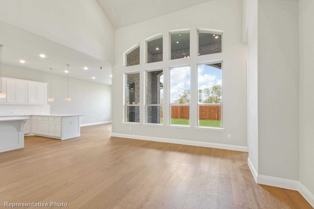 unfurnished living room with light hardwood / wood-style floors and high vaulted ceiling