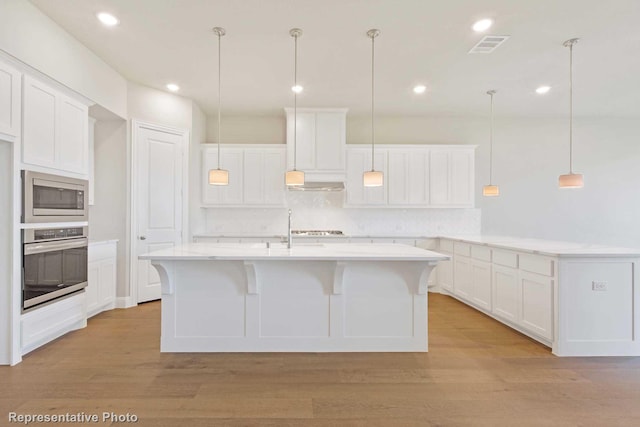 kitchen with white cabinets, a kitchen island with sink, and appliances with stainless steel finishes