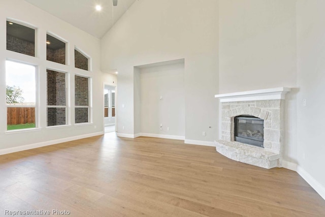 unfurnished living room featuring a fireplace, light hardwood / wood-style flooring, and high vaulted ceiling