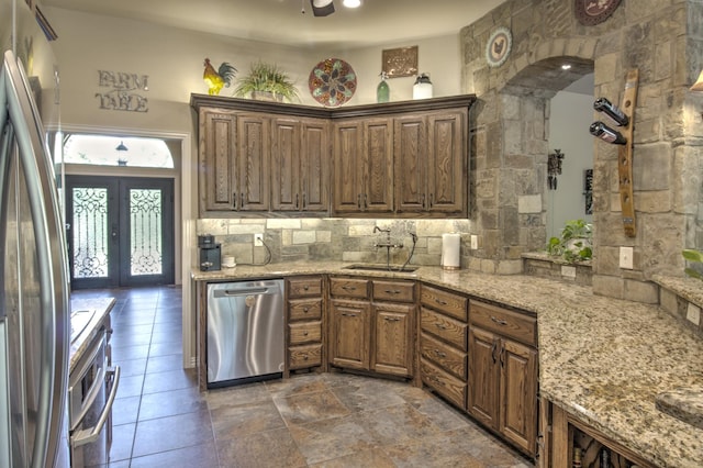 kitchen with french doors, sink, backsplash, light stone counters, and stainless steel appliances