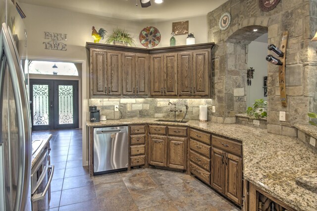 kitchen featuring light stone countertops, pendant lighting, sink, kitchen peninsula, and ceiling fan