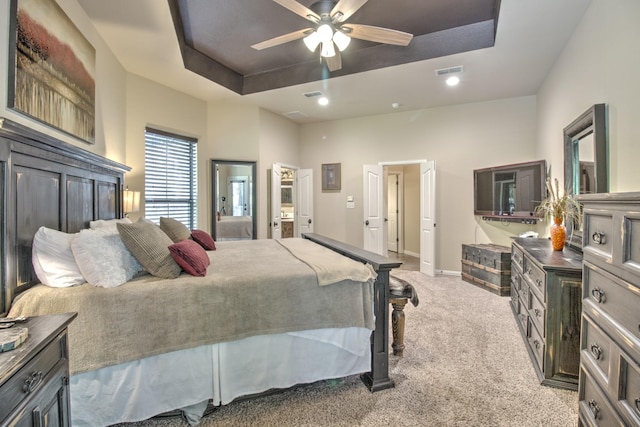 bedroom featuring ceiling fan, a raised ceiling, and light carpet