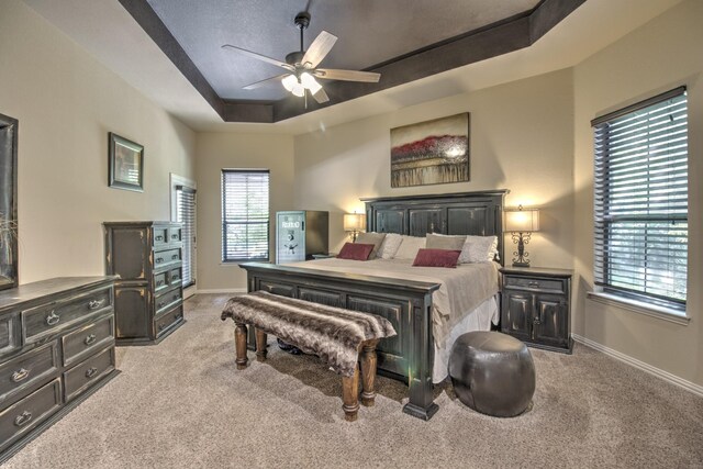 bedroom featuring ceiling fan, a raised ceiling, and light carpet