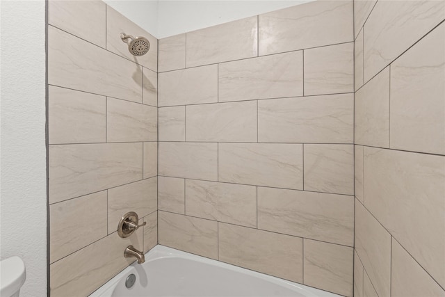 bathroom featuring toilet and tiled shower / bath