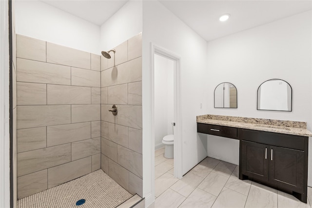 bathroom with vanity, toilet, and tiled shower