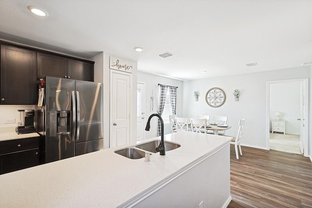 kitchen featuring dark wood-type flooring, stainless steel fridge, dark brown cabinets, and sink