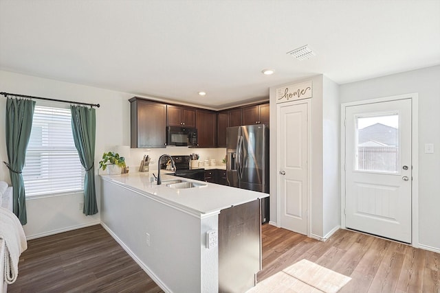 kitchen featuring sink, black appliances, plenty of natural light, and dark brown cabinetry