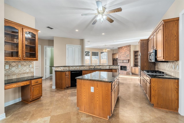 kitchen with appliances with stainless steel finishes, built in desk, a center island, decorative backsplash, and sink