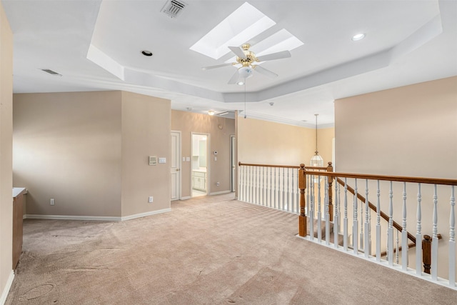 unfurnished room featuring ceiling fan, a skylight, light carpet, and a raised ceiling